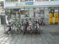 Two racks full of bicycles in front of a natural food store