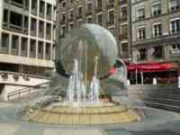 Fountain with many sprays of water, some splashing against a large plate sculpture