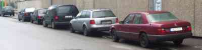 Cars parked over the curb, half on the sidewalk