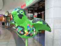 Green sparrow sculpture with pegs all over it and bits of colored plastic stuck onto the pegs