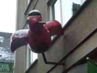 Sculpture of a red sparrow smoking and wearing a cap with a red star