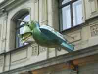 Sculpture of a blue and green sparrow what may be a flowerbud