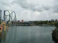 Lake with roller coaster to left, various amusement-park buildings in background, and landscaping